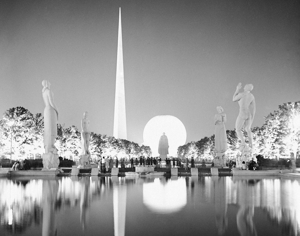  A view taken from the side of one of the many lagoons at the New York World's Fair on July 7, 1939. Light brings out some of the wondrous beauty as erected at the "World of Tomorrow". The famous statue of George Washington is silhouetted against the lighted Perisphere. (AP Photo)